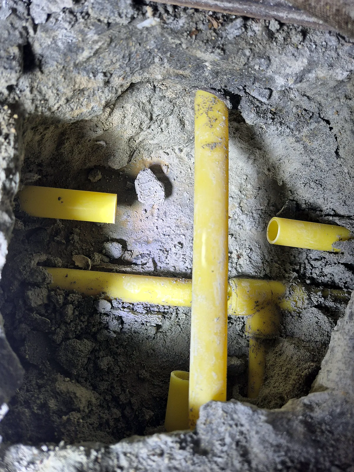 바닥 구멍 아래로 엇갈려 지나가는 노란 배관